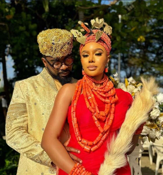 Uzor Arukwe in a gold brocade outfit standing behind Nancy Isime in red traditional Edo attire and coral beads for Loving Itohan.