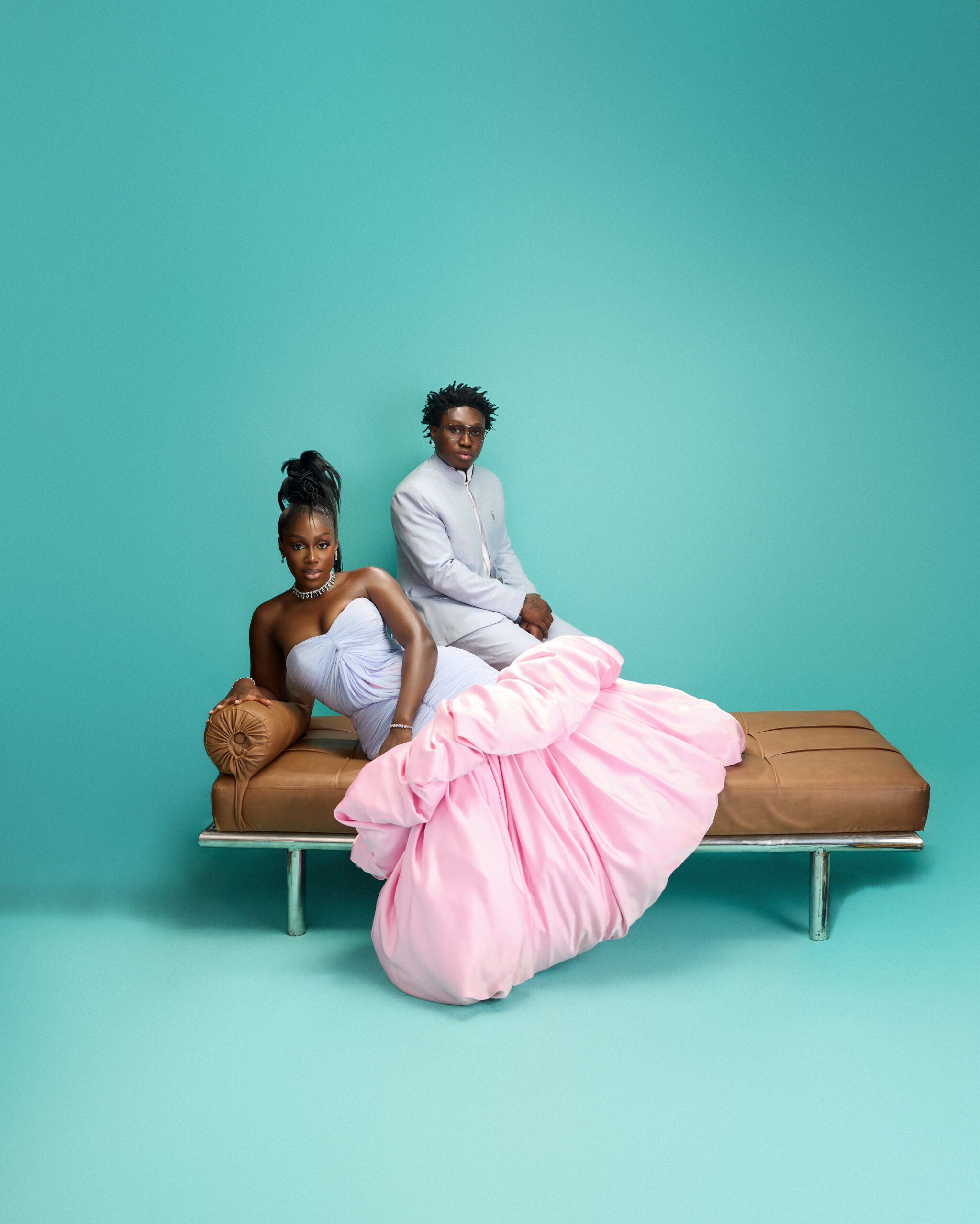 Davita Omoniyi reclining on a tan leather bench in front of Zlatan Ibile against a teal backdrop.