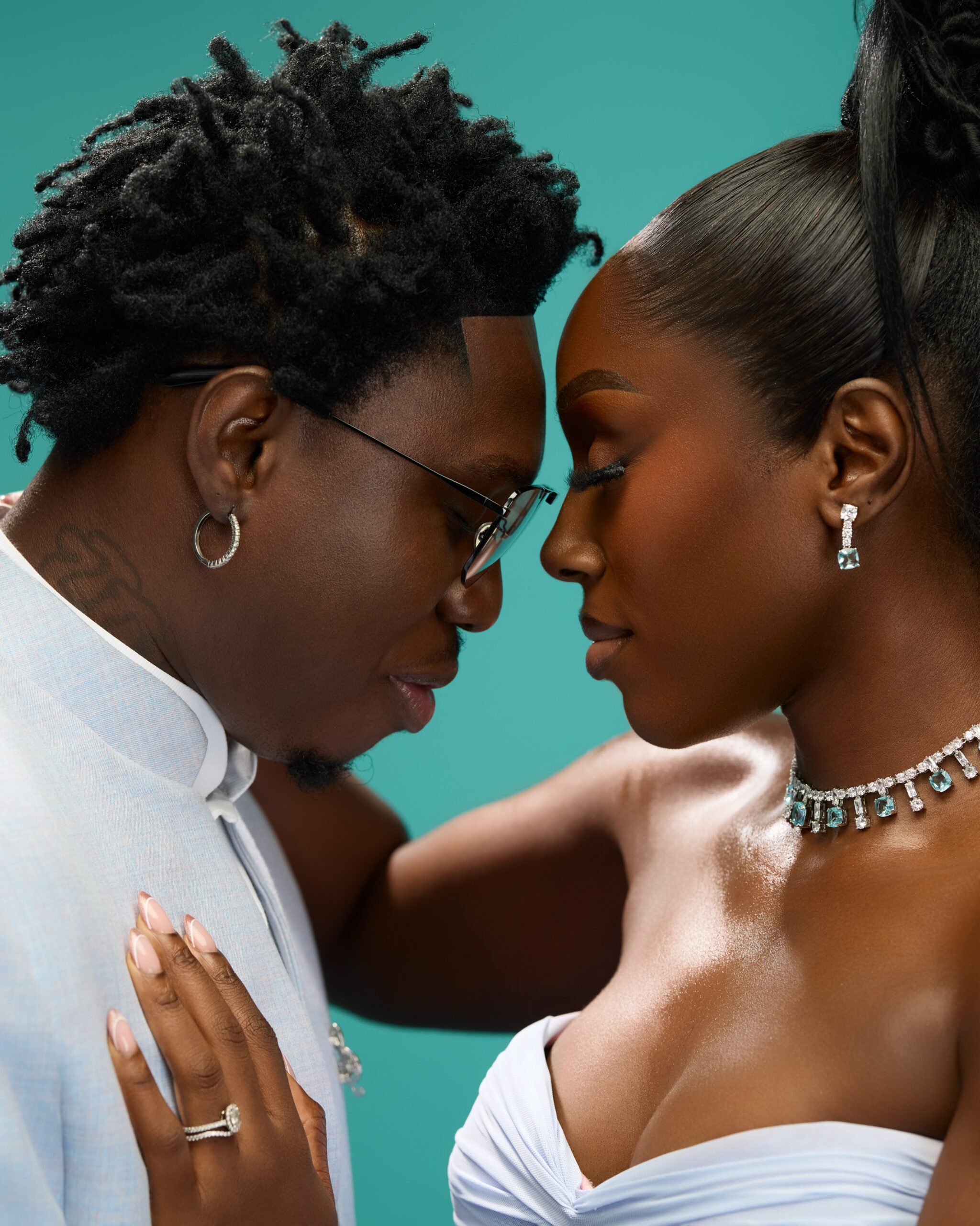 Zlatan Ibile touching foreheads with Davita Omoniyi highlighting diamond earrings and a tennis necklace with aquamarine accents.