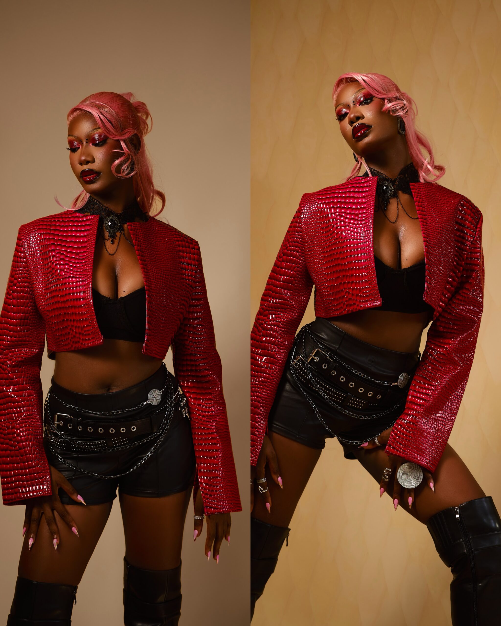 Tomi Ojo with pink waves hair wearing a cropped red crocodile-print jacket, black crop top, and leather shorts with chain belts.