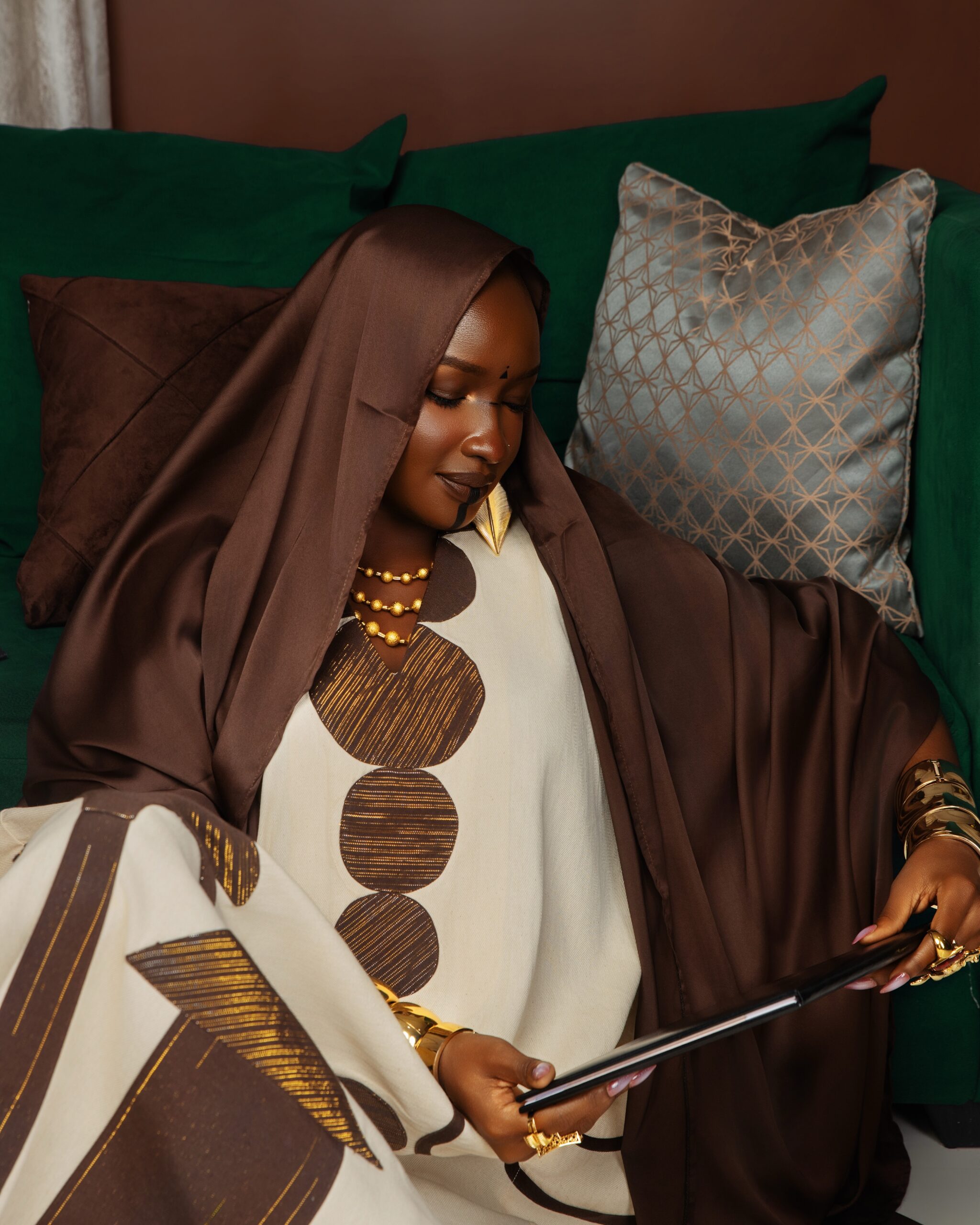 Saskay wearing a brown silk veil and kaftan holding a VUB Brussels School of Governance diploma case.