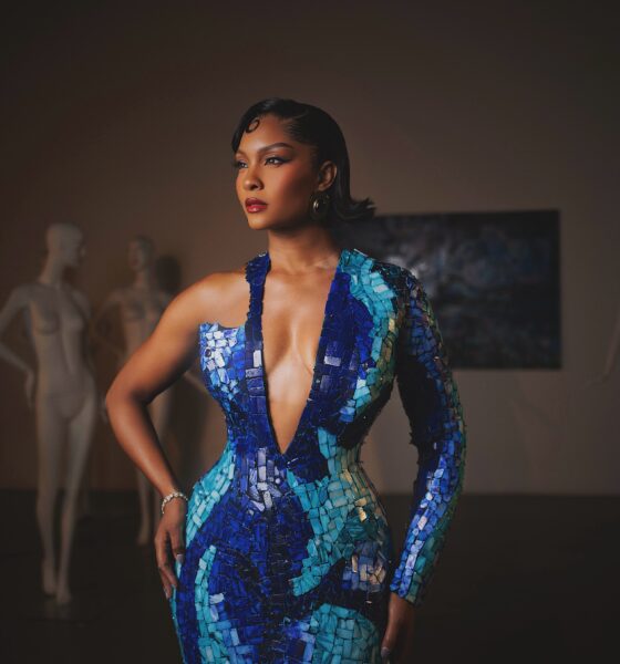 Osas Ighodaro wearing a deep plunge blue mother-of-pearl mosaic gown with one long sleeve.