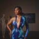 Osas Ighodaro wearing a deep plunge blue mother-of-pearl mosaic gown with one long sleeve.