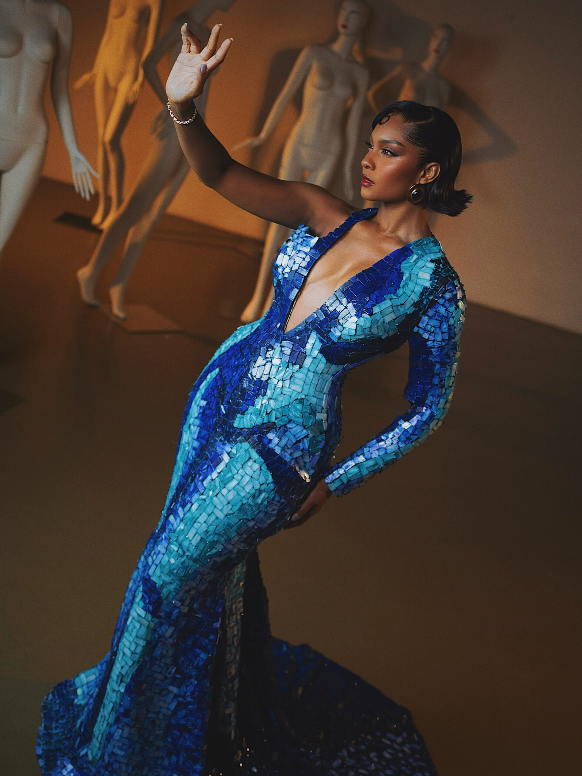 Osas Ighodaro wearing a plunging one-shoulder blue mosaic gown with retro finger waves hair.