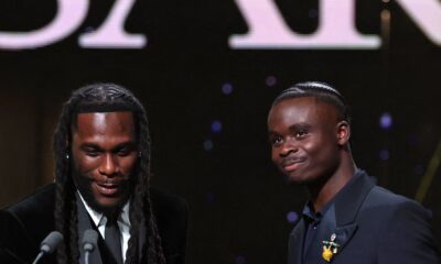 Burna Boy shaking hands with Bukayo Saka at the podium during the 2026 Ballon d’Or ceremony in London.