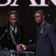 Burna Boy shaking hands with Bukayo Saka at the podium during the 2026 Ballon d’Or ceremony in London.