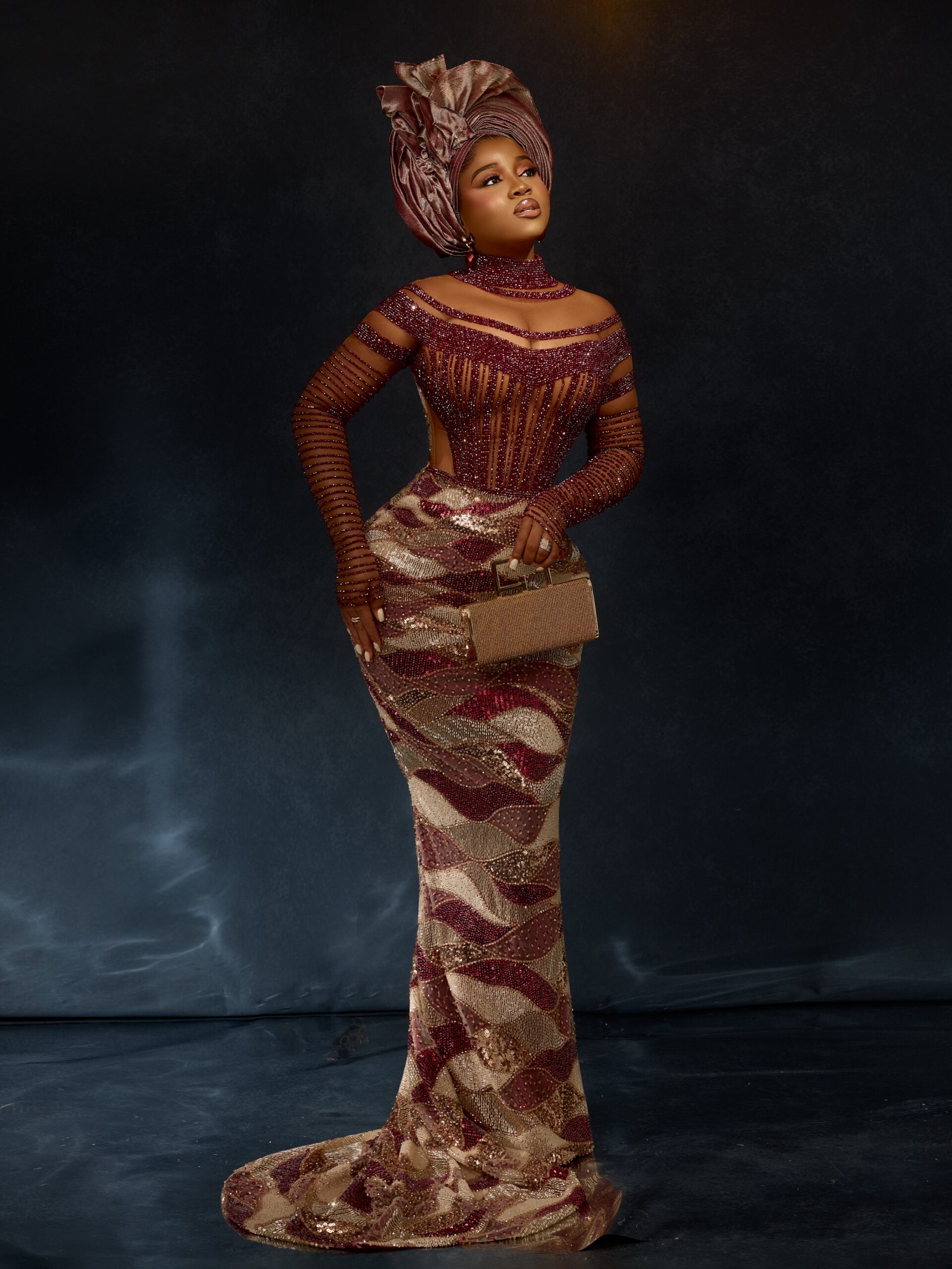 Veekee James in a wine red sheer corset gown with gold wave sequin embellishments and a dusty rose metallic gele for Zlatan Ibile and Davita Omoniyi's wedding.