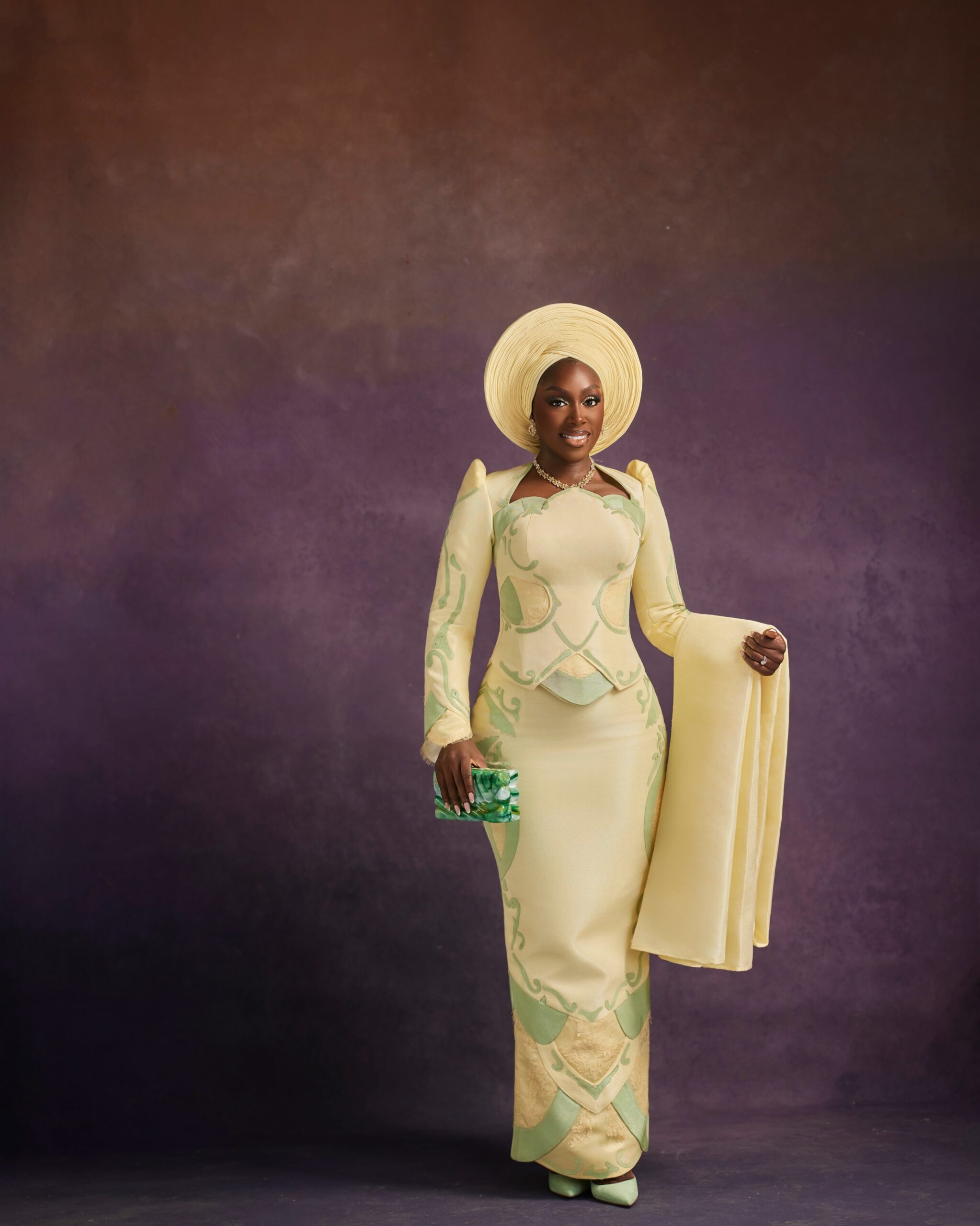 Davita Omoniyi in a pale lemon-yellow Mazelle Bridal two-piece set with mint-green floral appliqué, flared cuffs, and a green marble clutch bag.