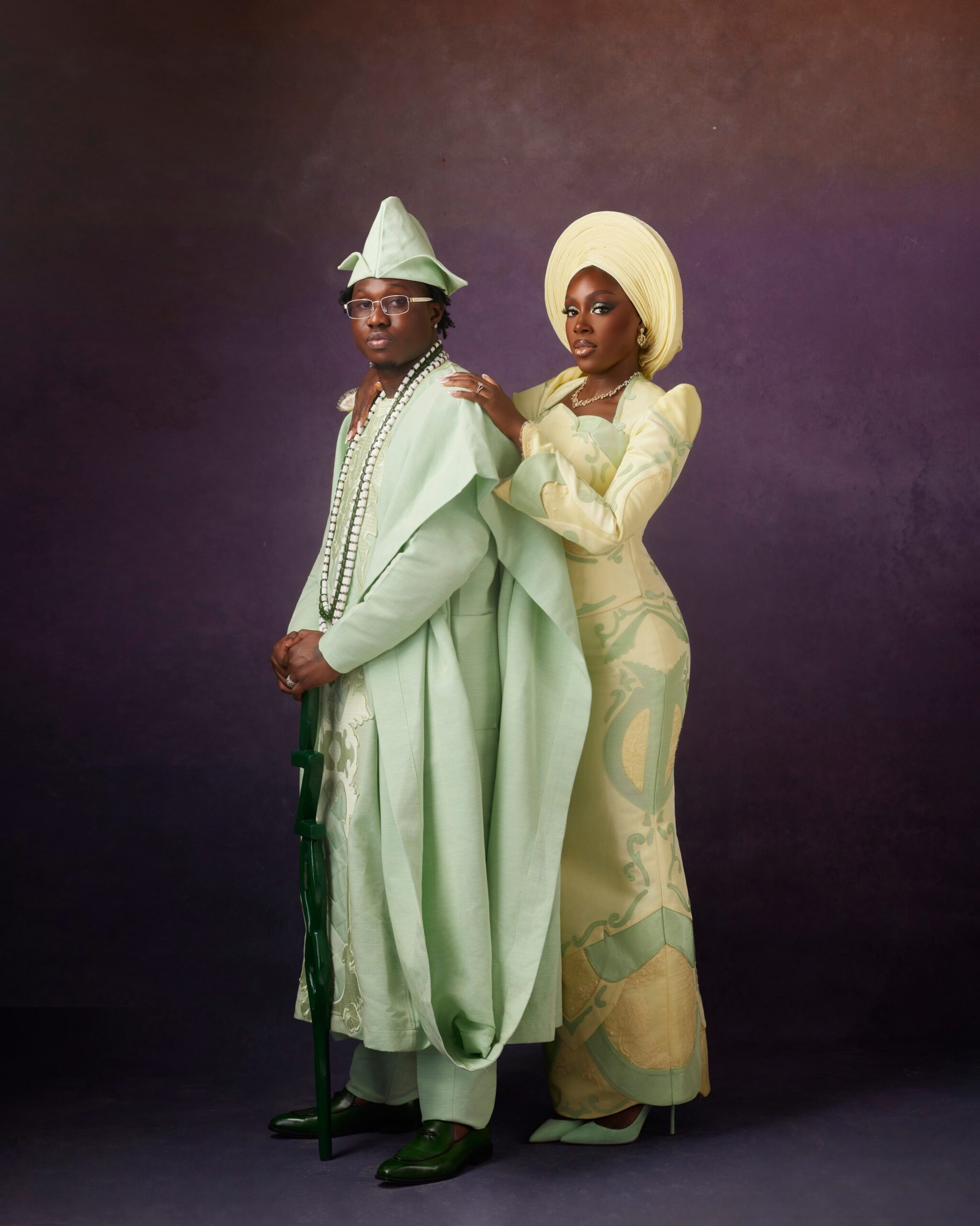 Davita Omoniyi placing her hand on Zlatan Ibile's shoulder while he wears a mint-green Agbada and multi-strand white beaded necklaces.