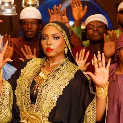 Yemi Alade wearing a black and gold-embroidered abaya with traditional gold jewellery in the Alhaja music video.