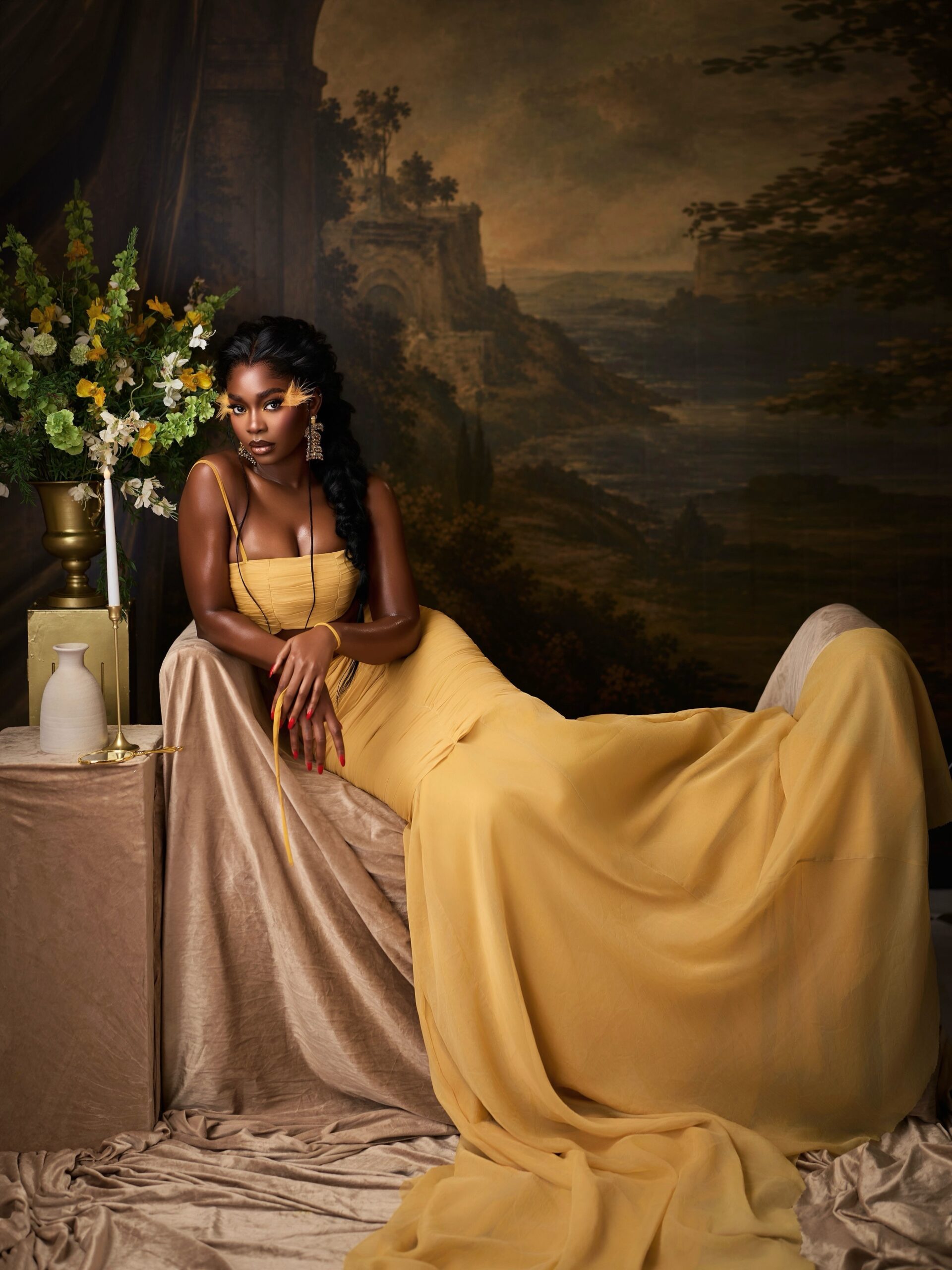 Dede Ashiogwu sitting beside a floral arrangement in a butter yellow bandeau and maxi skirt set.