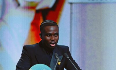 Bukayo Saka standing behind the podium holding the 2026 Socrates Award plaque at the Ballon d’Or ceremony in London.