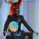 Bukayo Saka standing behind the podium holding the 2026 Socrates Award plaque at the Ballon d’Or ceremony in London.