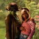 Cynthia Erivo wearing dark-rooted blonde side bangs with Ayoade Bamgboye in sunglasses and green body paint in front of a retro painted backdrop.