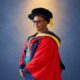 Folorunso Alakija wearing a red doctoral gown, black cap, and tinted glasses.