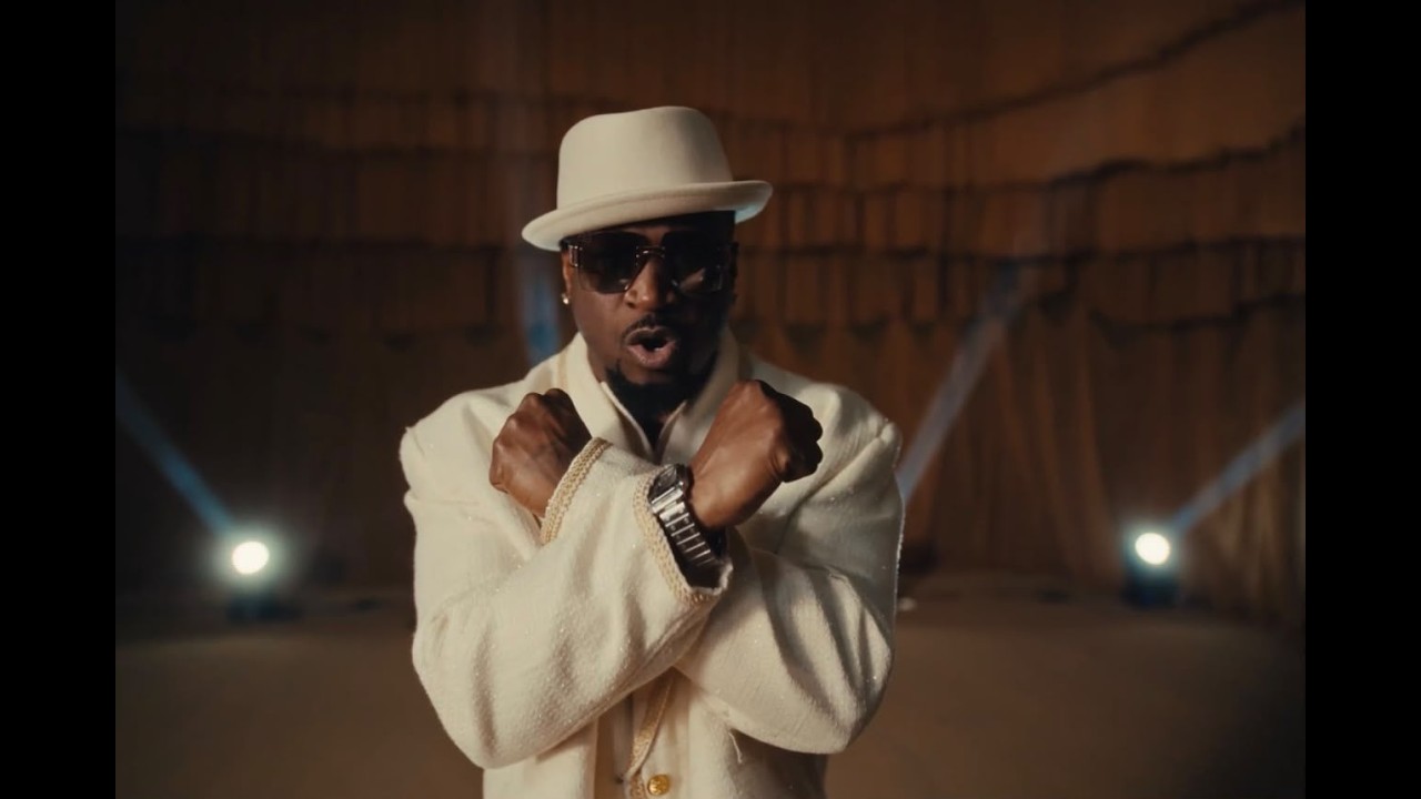 Mr P wearing a cream double breasted suit white fedora and sunglasses in Chukwu Mee music video