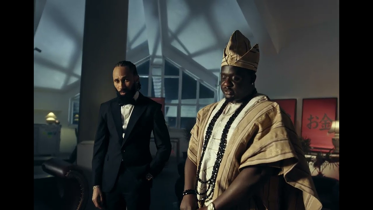 Phyno in a black suit beside Wande Coal in traditional Yoruba Agbada and Fila cap in the Ndewo music video directed by TG Omori.