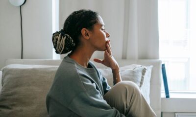 A thoughtful young woman sits in a relaxed pose in a serene bedroom, reflecting peacefully. Photo credit: Alex Green/Pexels.